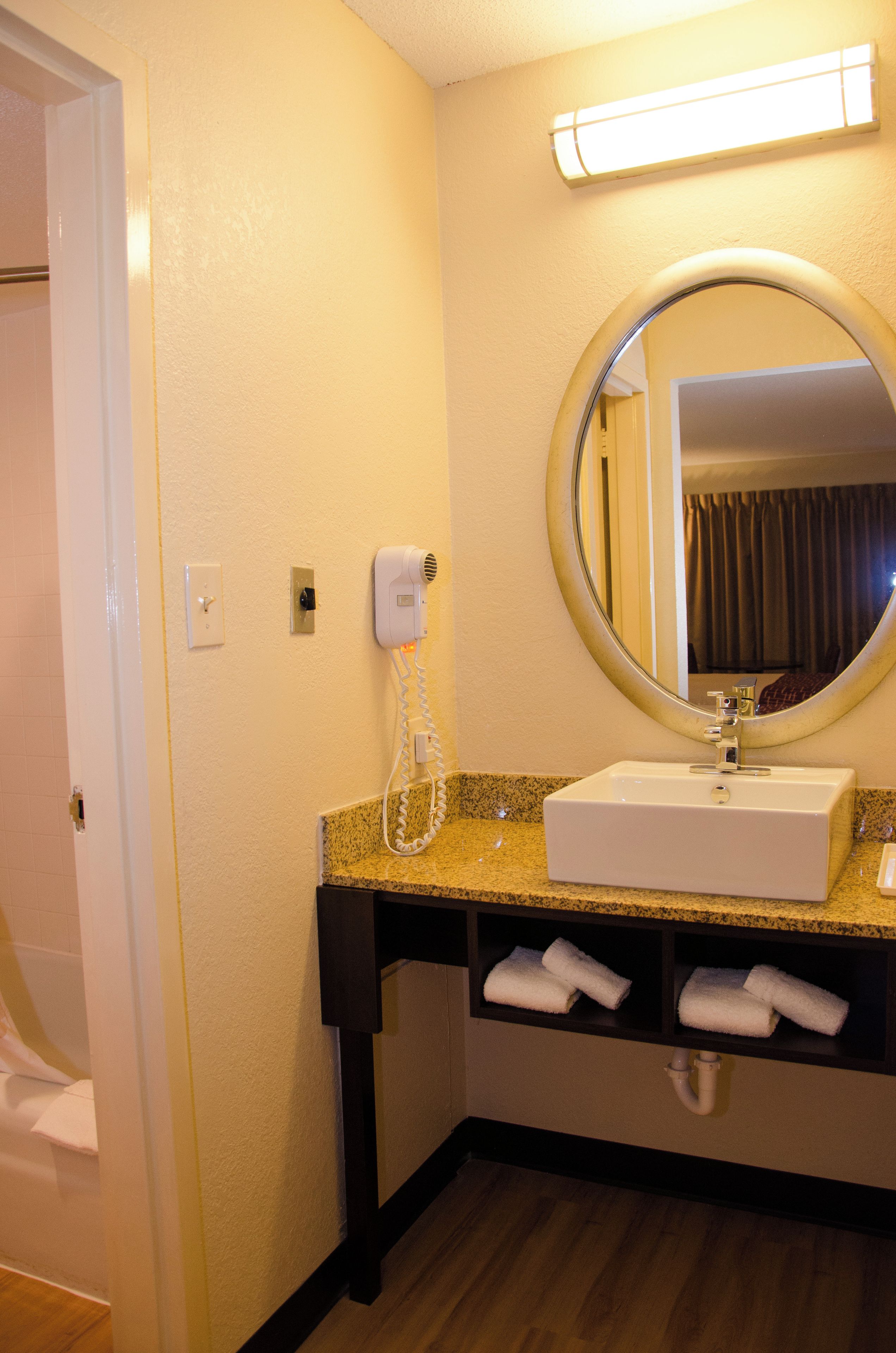 A hotel bathroom with a sink, mirror, towel rack, and a hairdryer.