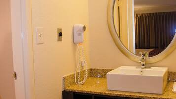A hotel bathroom with a sink, mirror, towel rack, and a hairdryer.