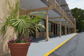A building with a covered walkway, potted plants, and a clear sky.