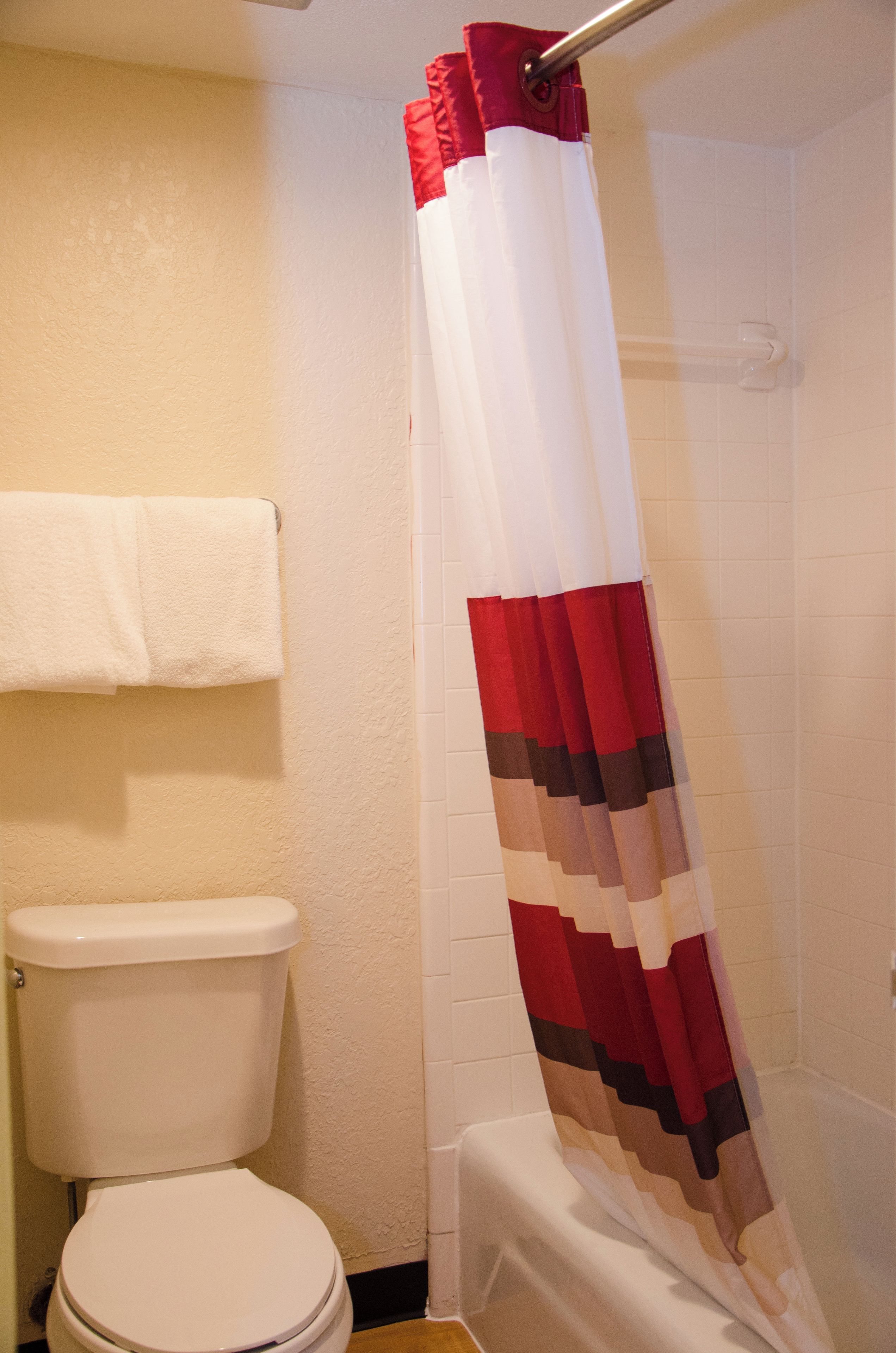 A bathroom with a white toilet, a towel hanging on the wall, and a shower curtain with a striped pattern.
