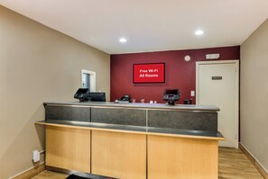 A hotel reception area with a counter, a private room sign, and a wall sign indicating free Wi-Fi availability. - Red Roof Inn Williamsburg (Williamsburg)