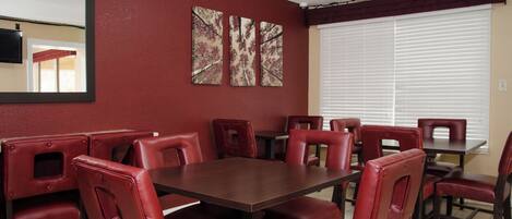 Un espace repas avec des banquettes rembourrées de tissu rouge et une table en bois foncé.