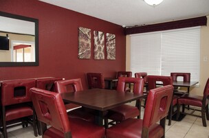 Un comedor con asientos tapizados en rojo y una mesa de madera oscura.