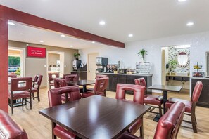 A restaurant with tables and chairs, a kitchen area, and a sign indicating free Wi-Fi availability. - Red Roof Inn Williamsburg (Williamsburg)