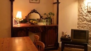 A dining area with a wooden table, chairs, a lamp, a mirror, and a television. - Llysyfran Farm B&B (Clarbeston Road)