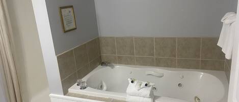 A bathroom with a bathtub, a framed certificate on the wall, and a towel on the edge.