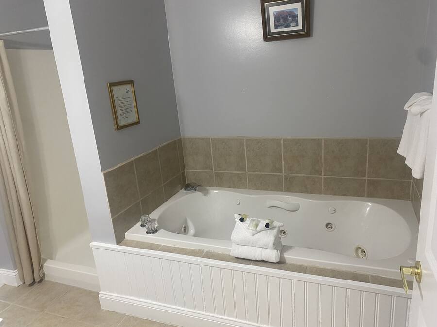 Un baño con bañera, un certificado enmarcado en la pared y una toalla sobre el borde.