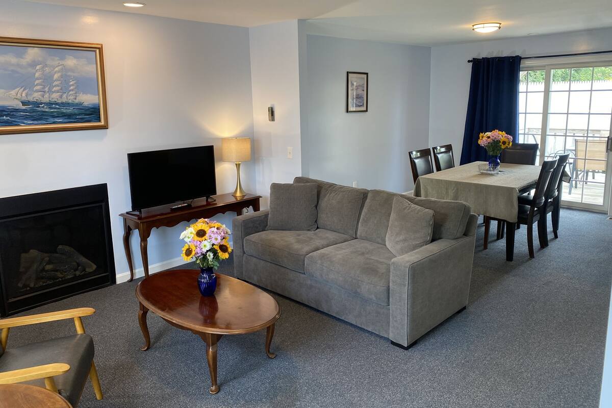 A living room with a sofa, TV, fireplace, and a dining area with a table and chairs.