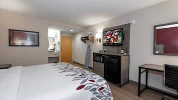 A hotel room with a large bed, a desk, a microwave, a television, and a small table.