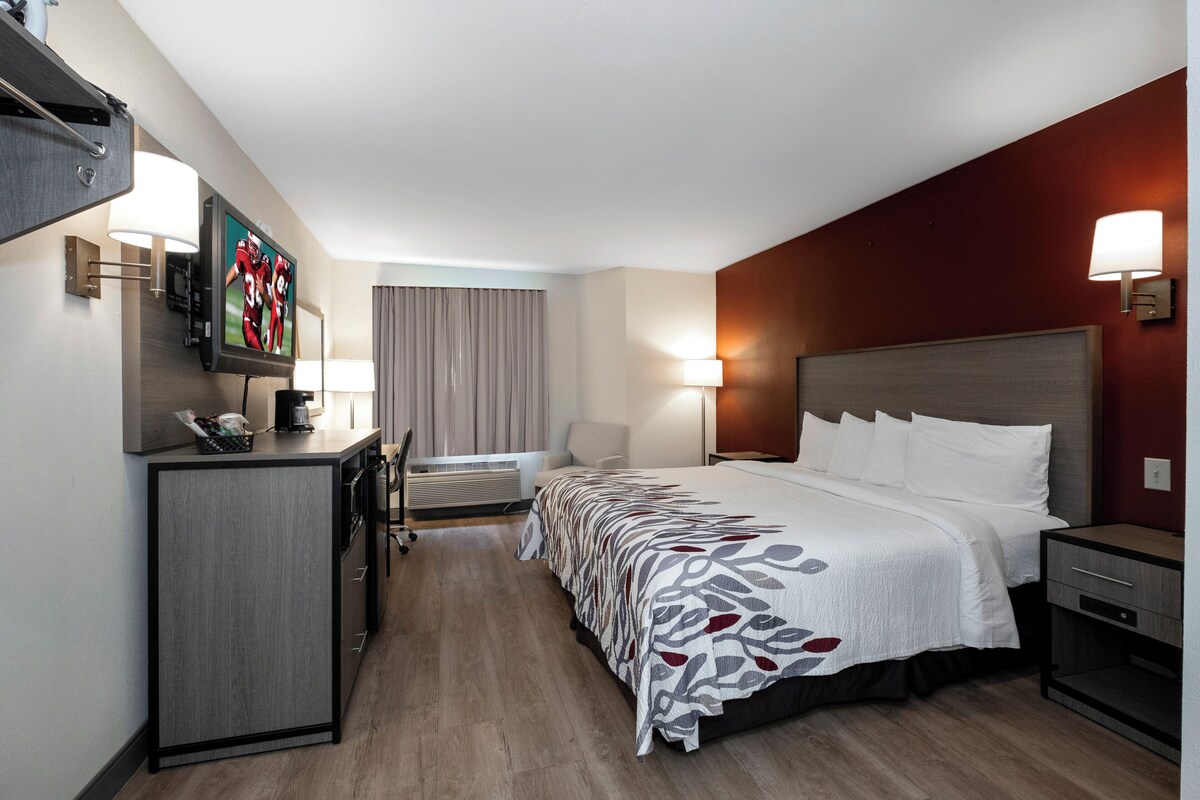 Une chambre d’hôtel avec un lit, un bureau, une télévision et une lampe.