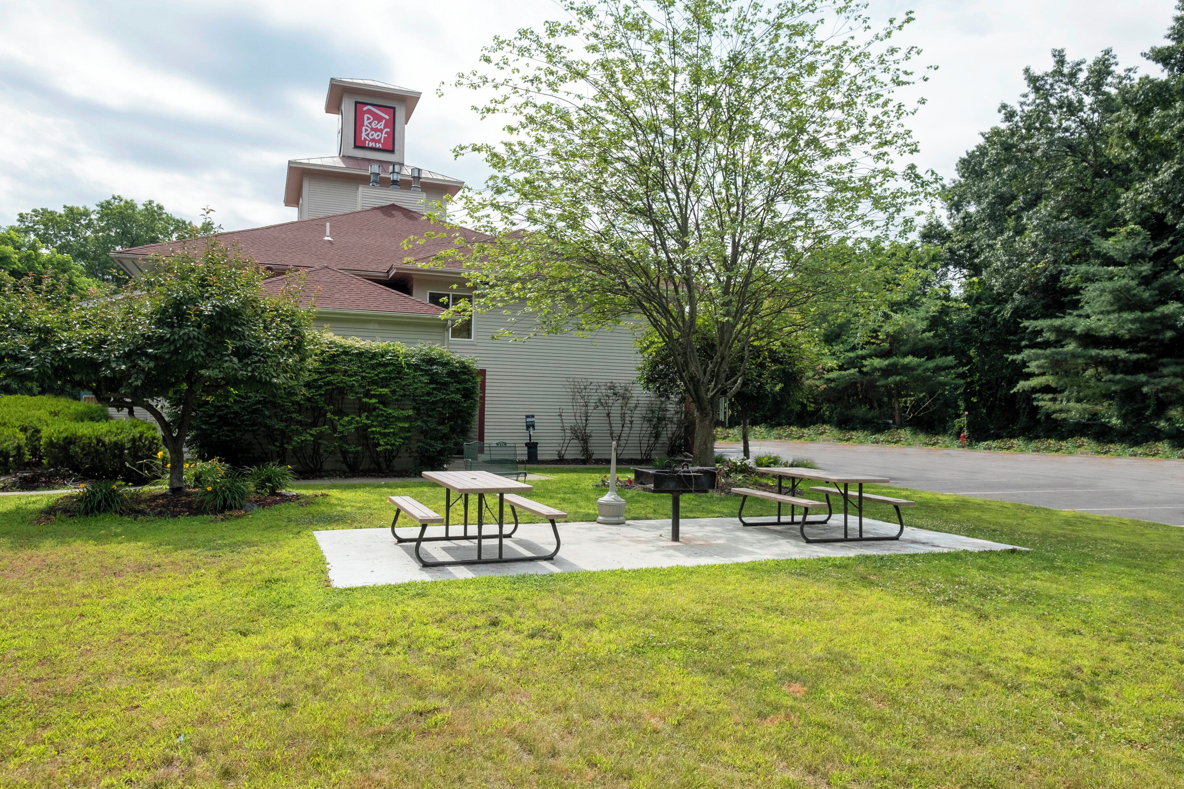 Un Red Roof Inn con un área de patio que incluye mesas de picnic y una parrilla.