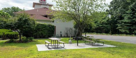 Un Red Roof Inn con un área de patio que incluye mesas de picnic y una parrilla.