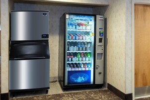 Una máquina expendedora con pantalla digital y un refrigerador con cerradura electrónica.