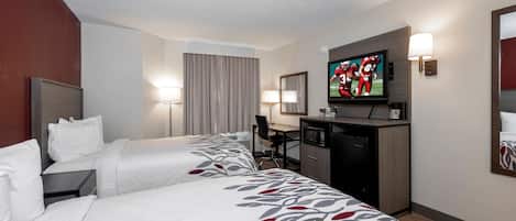 A hotel room with two beds, a desk, a television, and a microwave.