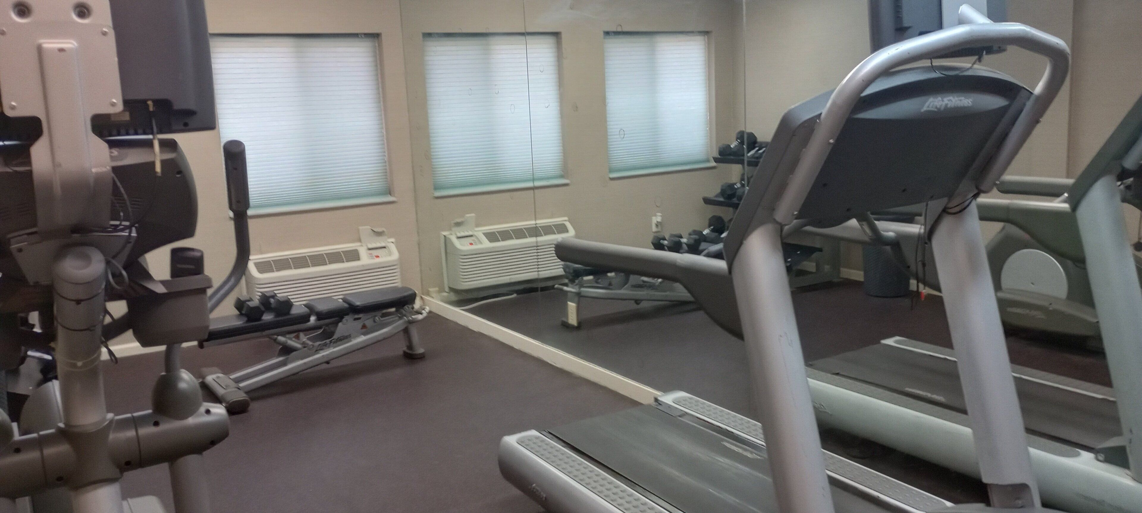 A gym with exercise equipment including treadmills and a rowing machine.
