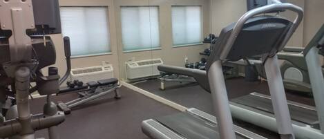 Un gimnasio con equipo de ejercicio, incluyendo cintas de correr y una máquina de remo.