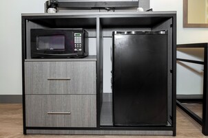 Una kitchenette con microondas, refrigerador y dos cajones.