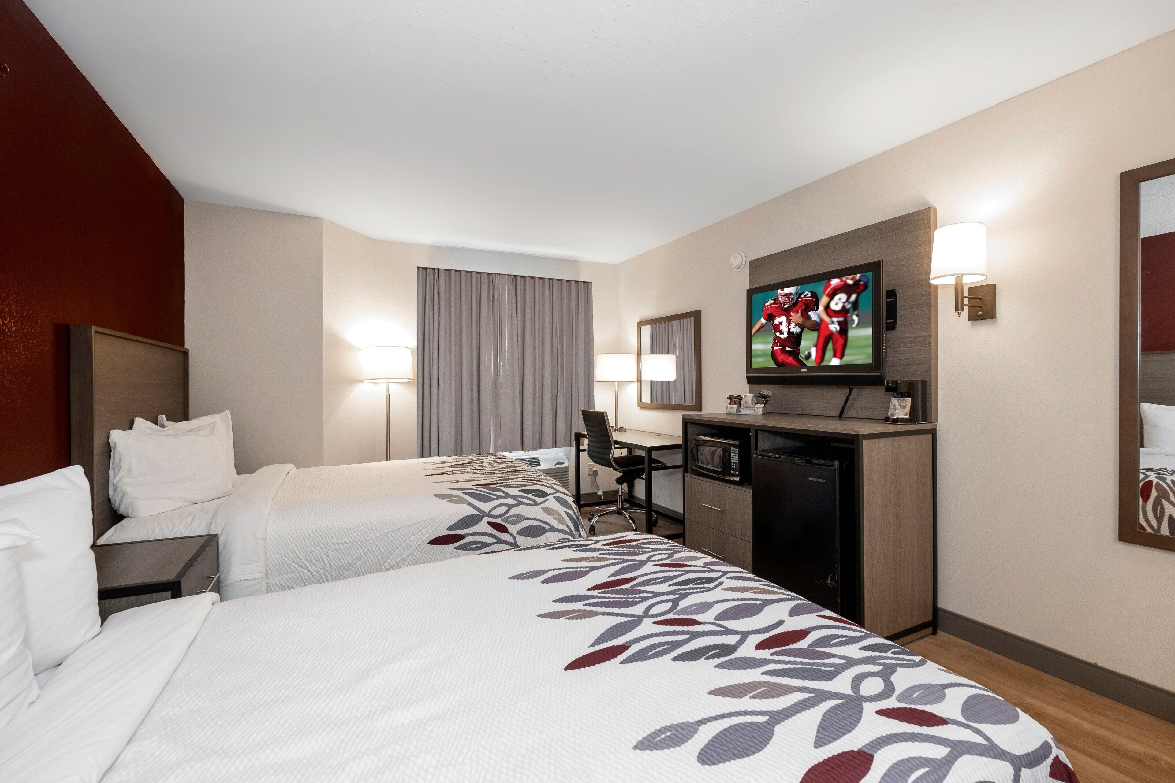 Una habitación de hotel con dos camas, un escritorio, un televisor y un microondas.