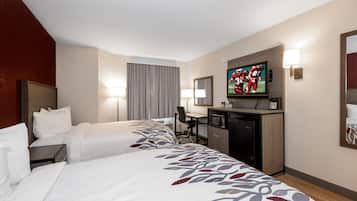 Una habitación de hotel con dos camas, un escritorio, un televisor y un microondas.