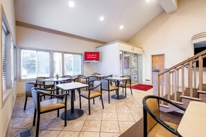 En restaurant med borde, stole, et skilt der viser gratis Wi-Fi og en trappe.