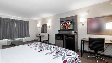 A hotel room with a bed, a desk, a TV, a chair, and a microwave.