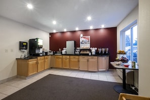A modern kitchen with wooden cabinets, a built-in coffee station, and a window with a view of the outside. - Red Roof Inn Clifton Park (Clifton Park)