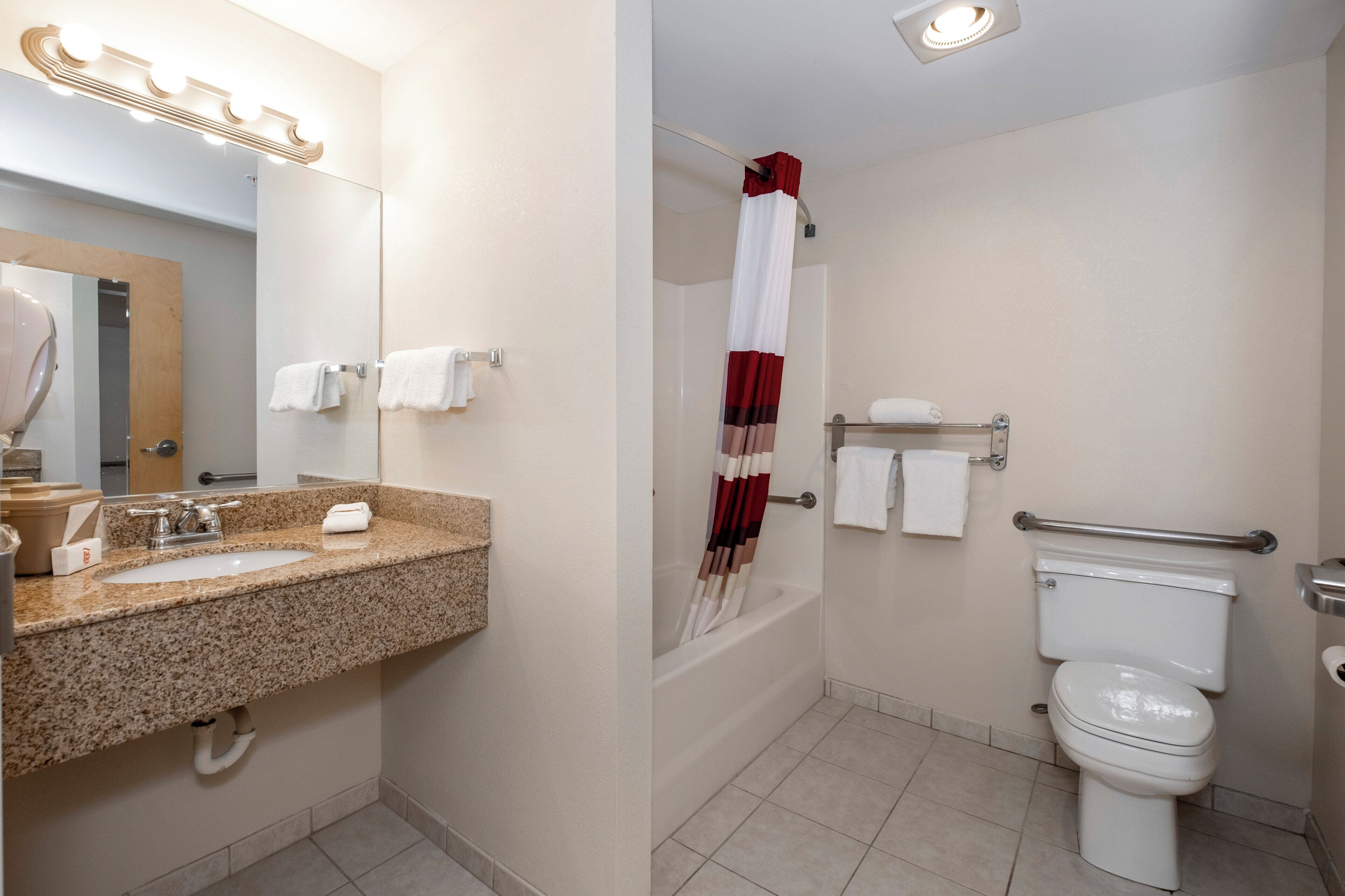 A bathroom with a sink, mirror, towel rack, toilet, and shower area.