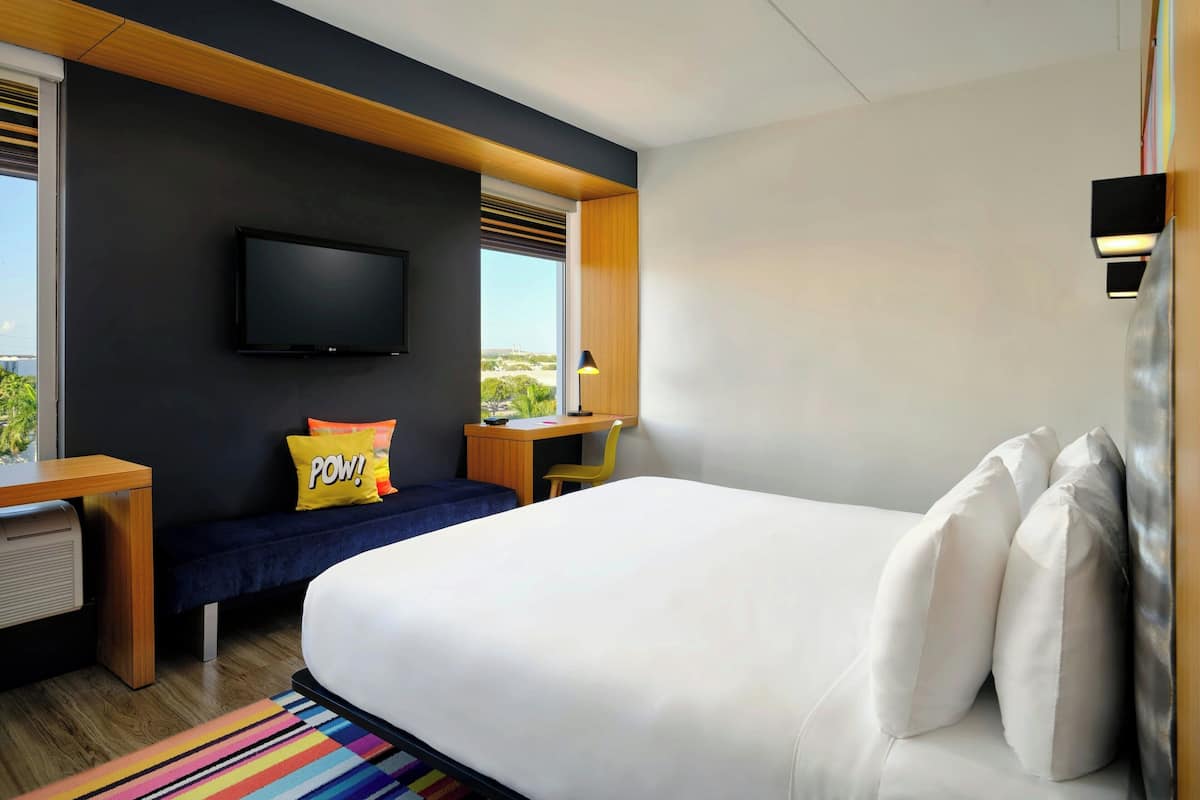 Un hotel moderno con una cama grande, un escritorio, un televisor y vistas al exterior.