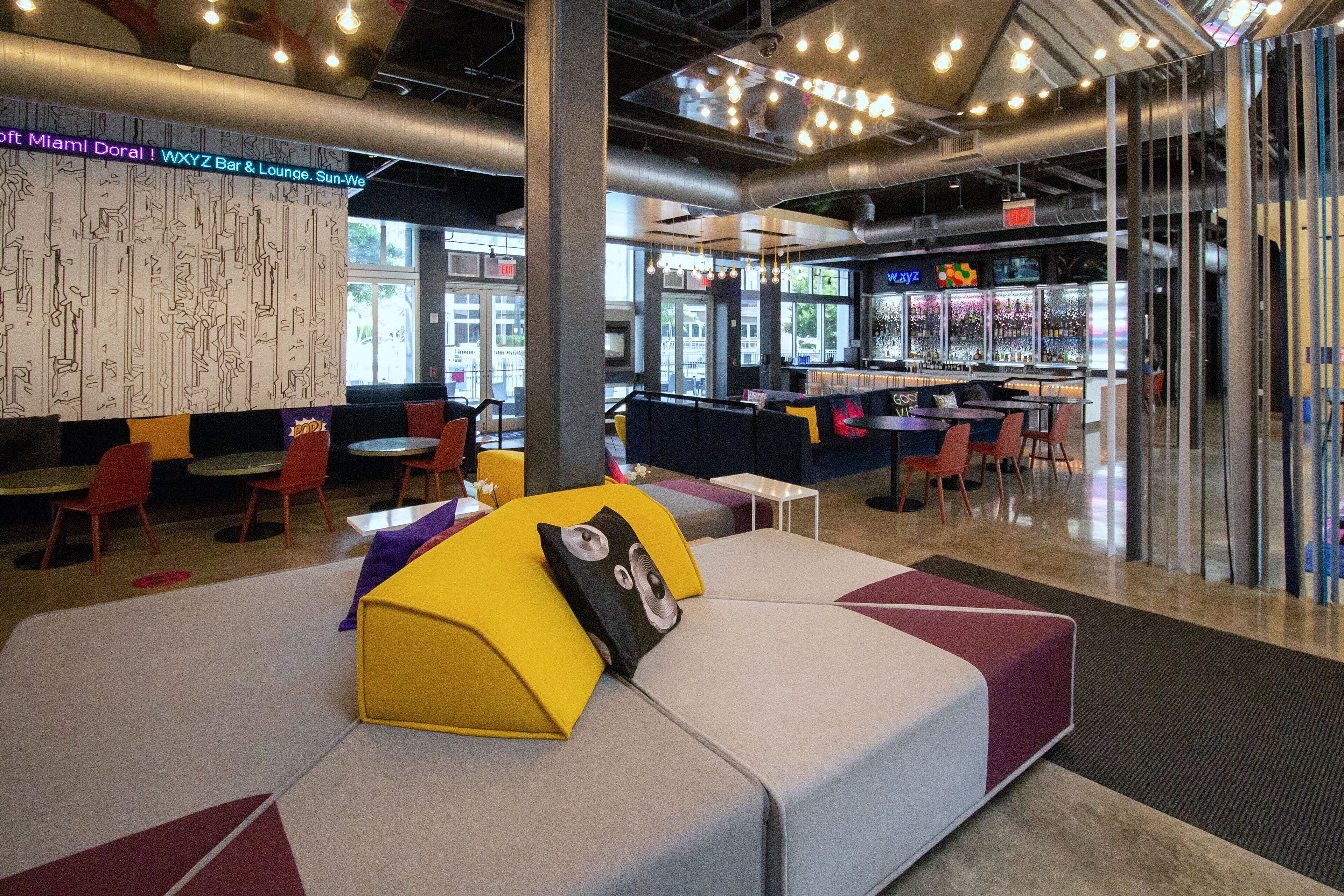 A modern lounge area with seating, a bar, and a view of the outside.