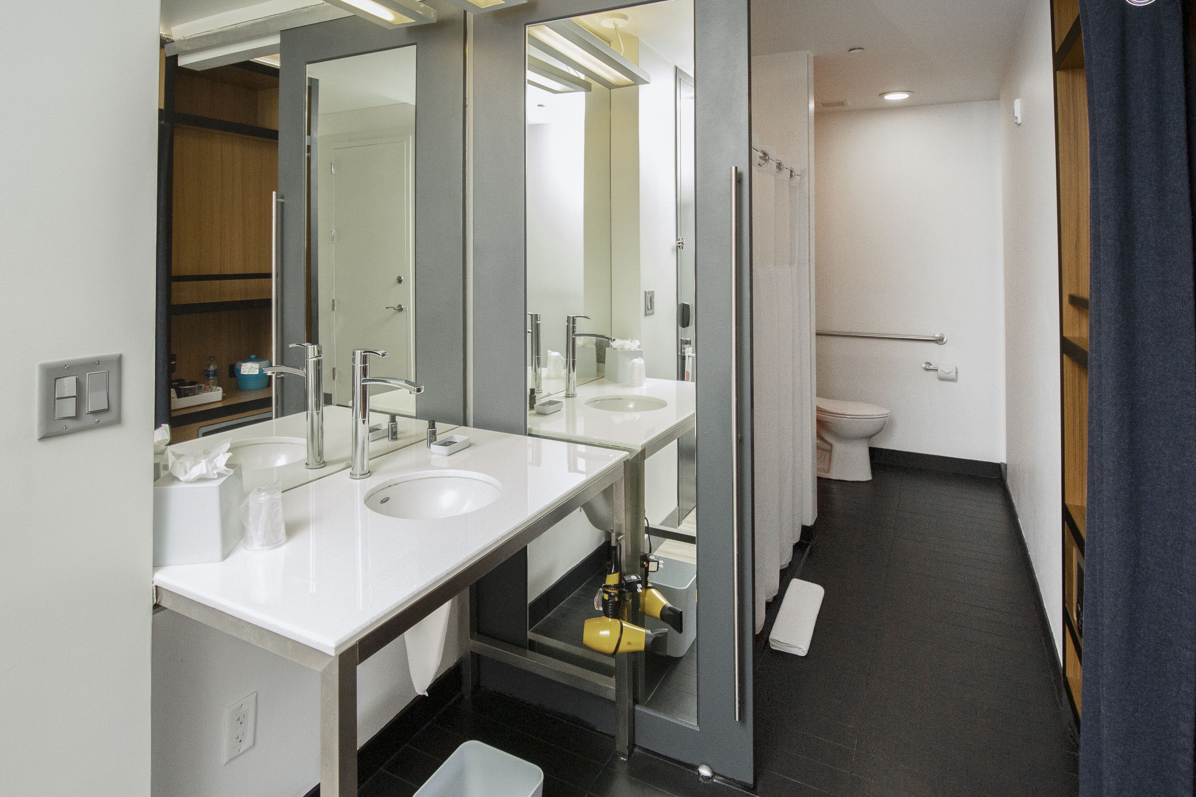 Ein modernes Badezimmer mit zwei Waschbecken, einem Spiegel und einer Toilette.