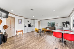 Una cocina amplia con electrodomésticos modernos, un comedor con sillas rojas y una sala de estar con sofá y mesa de centro.