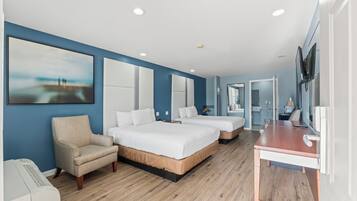A modern hotel room with a large bed, a desk, a chair, and a television.