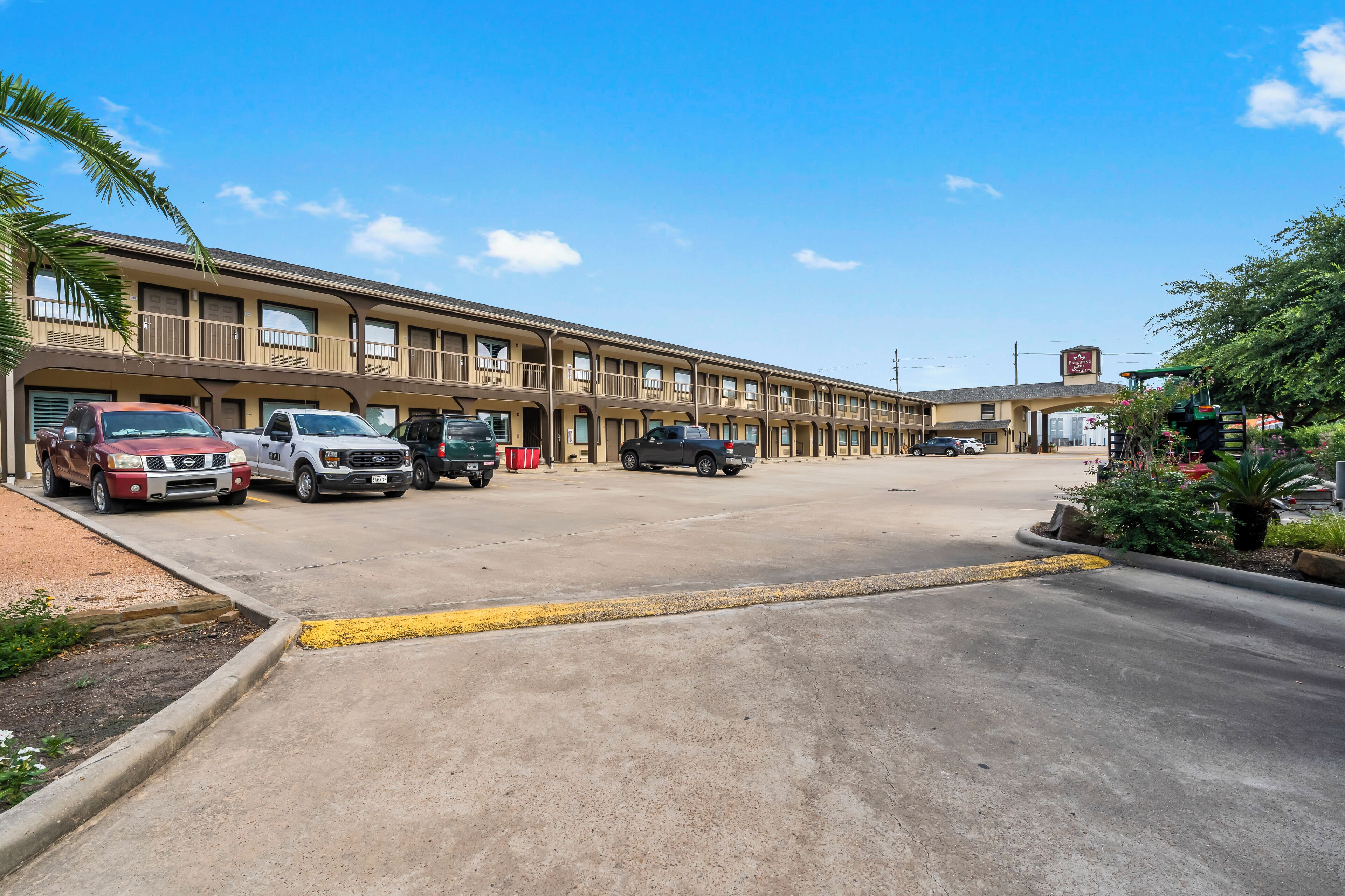 A multi-story motel with several parked vehicles in front.