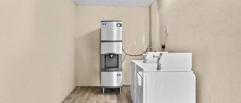 A compact utility room with a water dispenser and a washing machine.