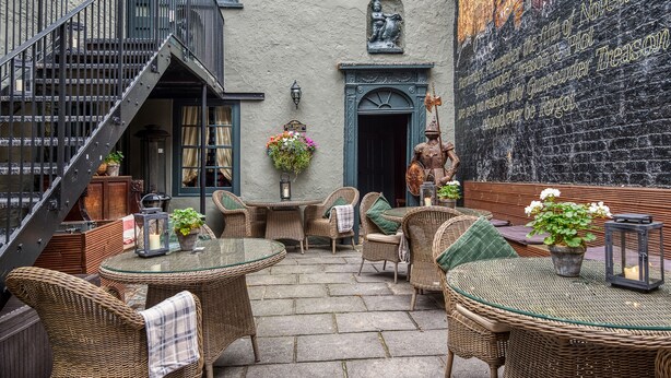 Een terras met rieten meubilair, een trap en een muurschildering.