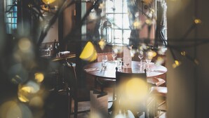 A dining area with round tables, chairs, and a menu stand. - The Globe (Exeter)