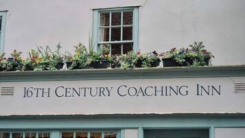 A building with a sign reading '16th Century Coaching Inn' and flower boxes on the roof.