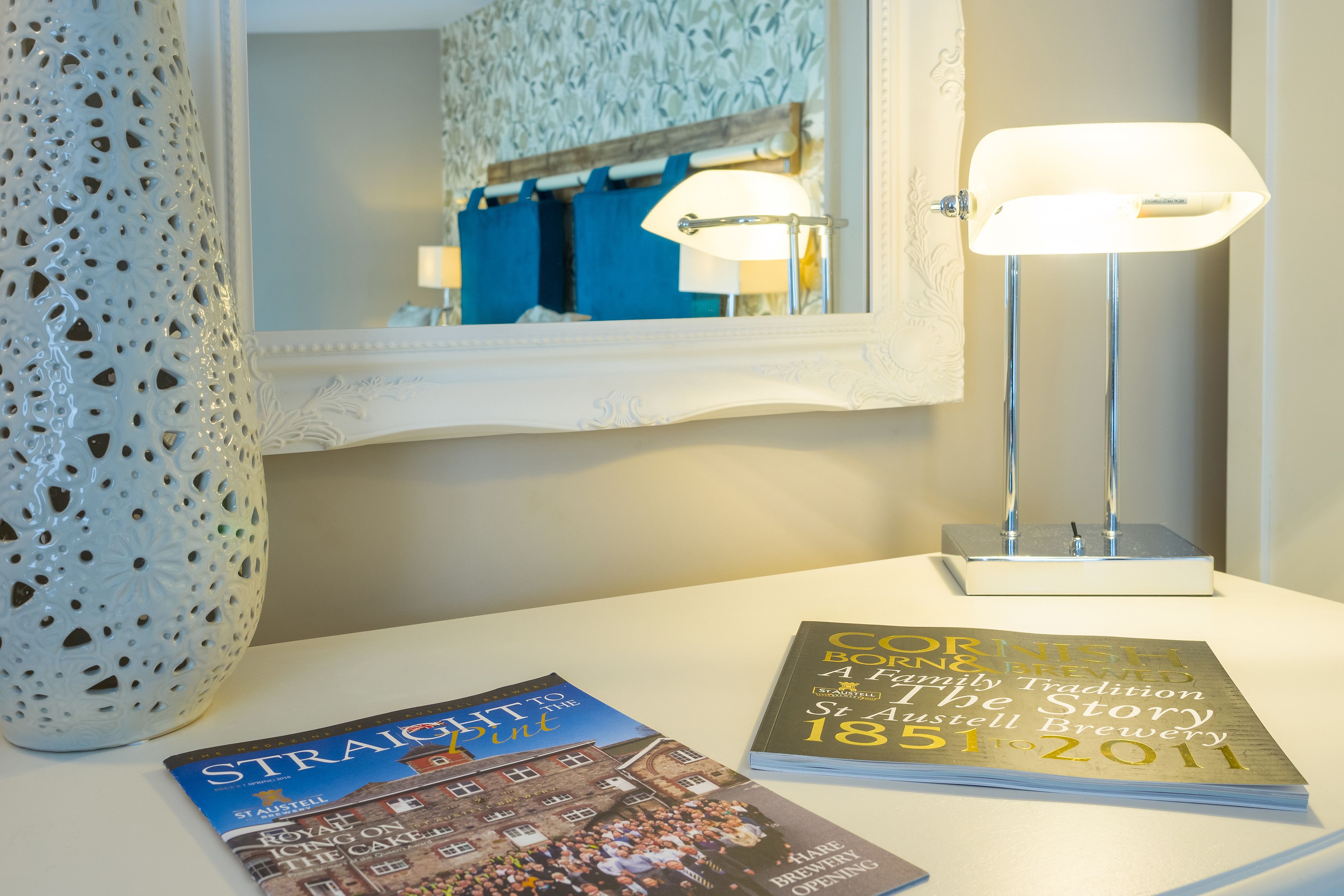Une table avec deux magazines et une lampe.
