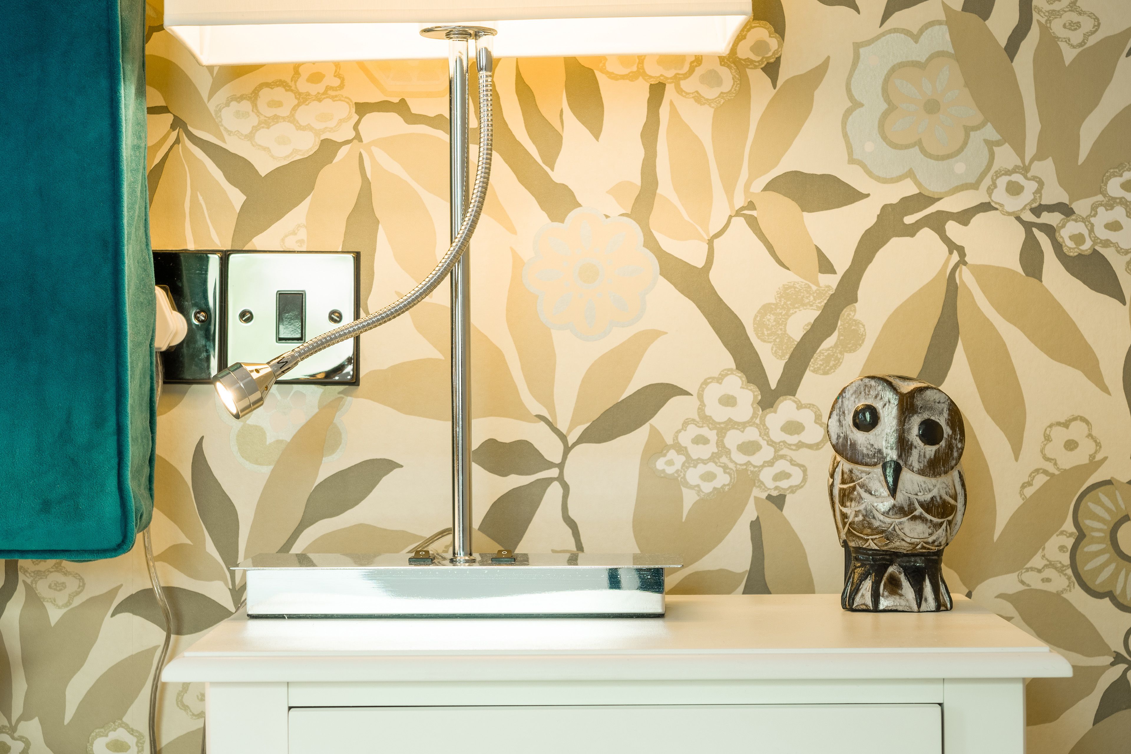 A bathroom with a white vanity, a showerhead, and a wall-mounted light fixture.