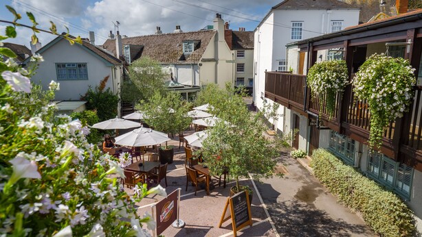 A courtyard with outdoor seating, surrounded by buildings with traditional architecture. - The Globe (Exeter)