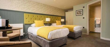 Quarto de hotel com duas camas, uma escrivaninha e uma cadeira.