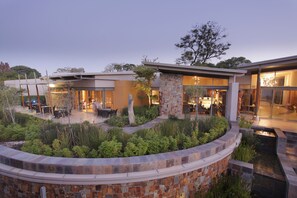 A modern house with a patio area, stone walls, and a small water feature.