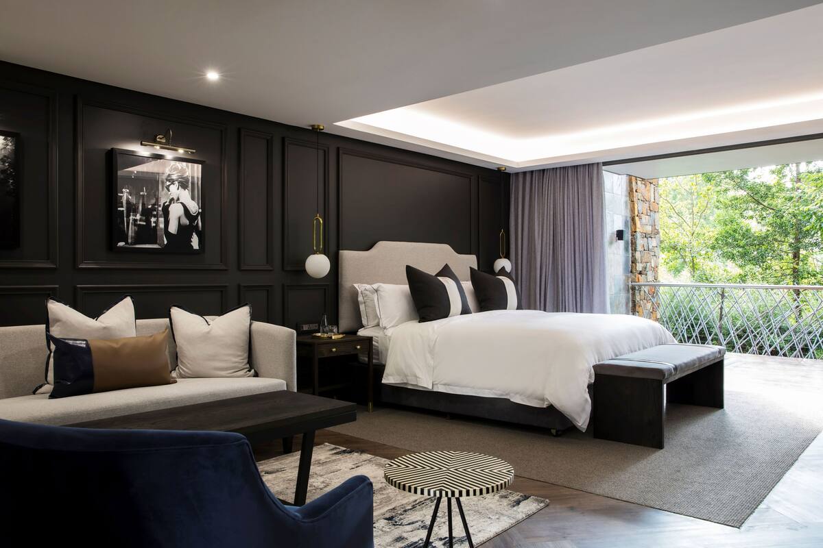 Een moderne slaapkamer met een groot bed, een bank, een salontafel en een aan de muur bevestigde televisie.