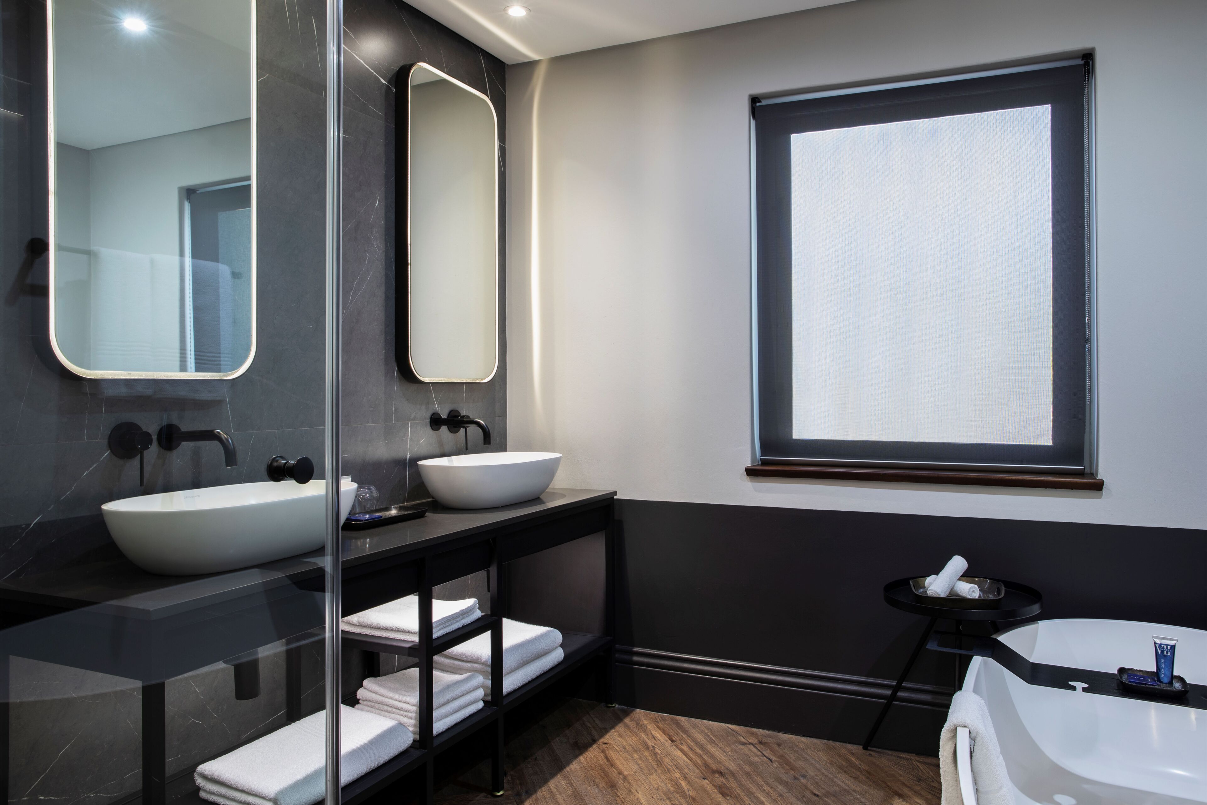 A modern bathroom with a large mirror, two sinks, and a window.