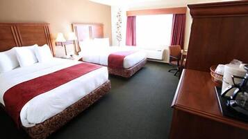 A hotel room with two beds, a desk, a chair, and a window with curtains.