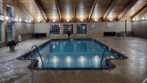An indoor swimming pool with a wooden ceiling, tiled walls, and a no diving sign.