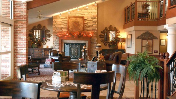 A spacious lobby with a stone fireplace, leather seating, and a staircase with a balcony.