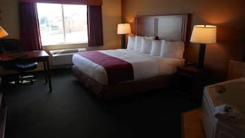 A hotel room with a large bed, two bedside lamps, a desk with a chair, and a window with curtains.