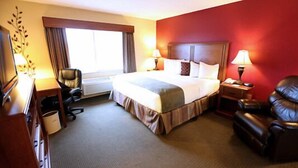 A hotel room with a large bed, a desk, a chair, and a window with curtains.