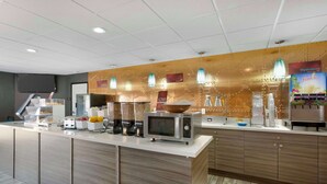 Een moderne keuken met een magnetron, koffieapparaat en een sapautomaat.